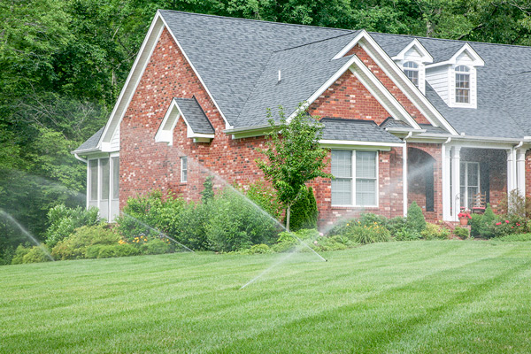 Brick home with sprinkler system watering lawn