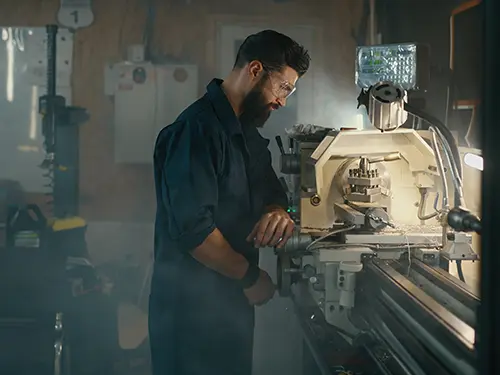 Machinist operating a metal lathe in a small shop